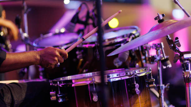Close up hands of a musician playing drum set in a concert. Motion image.
