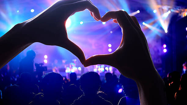 Crowd of Audience at during a concert with a heart shaped hands shadow